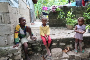  Jonas*, 10, Riccardo*, 8 and Jesula*, 7, sit where the front door to their house used to stand.