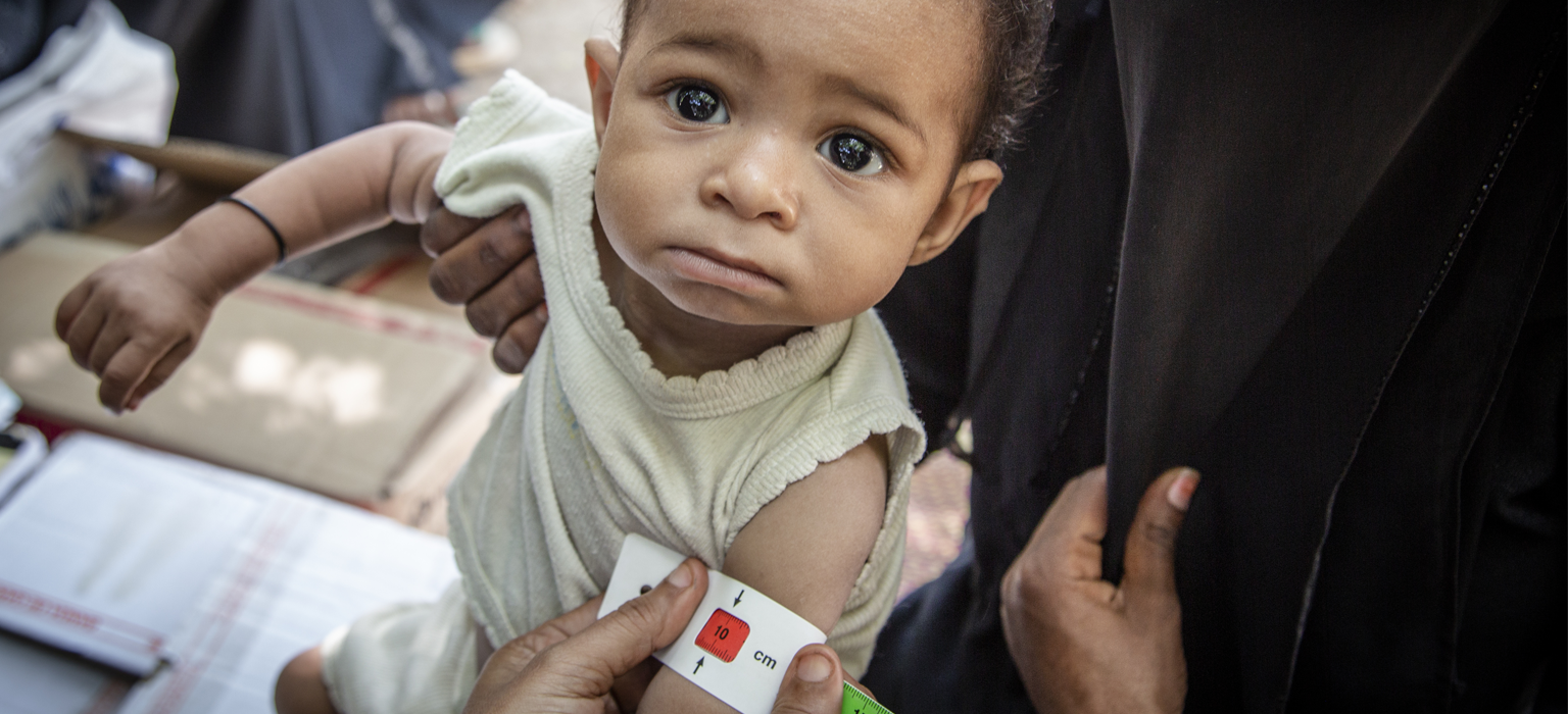 A child in front of aid provided by Save the Children