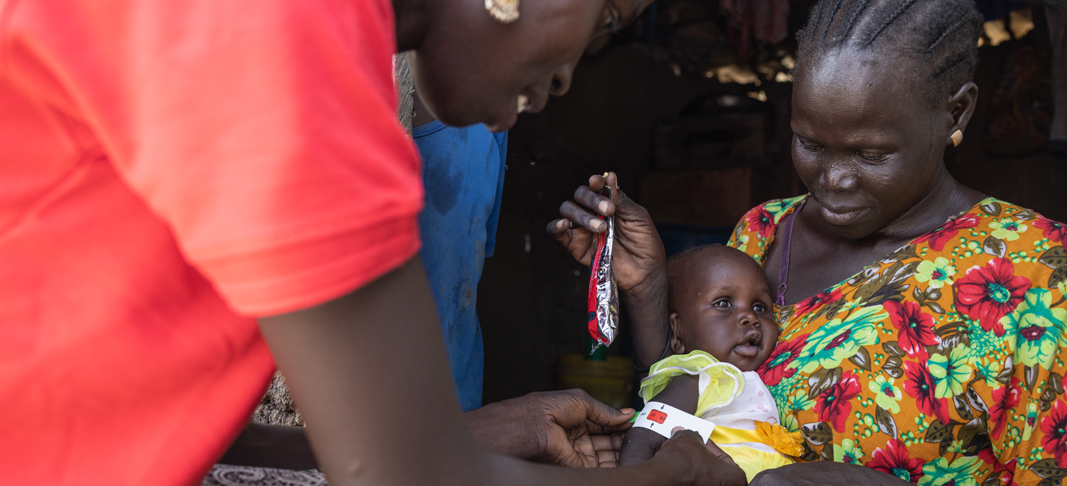 Save the Children aid worker assisting a mother and child