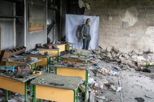 Borys*, 17, poses for a portrait at his damaged school outside of Kyiv.