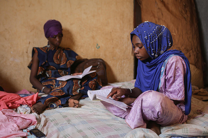 Kadidia, aged 14, and her friend Mariam studying after school at her home in Mopti region, Mali_