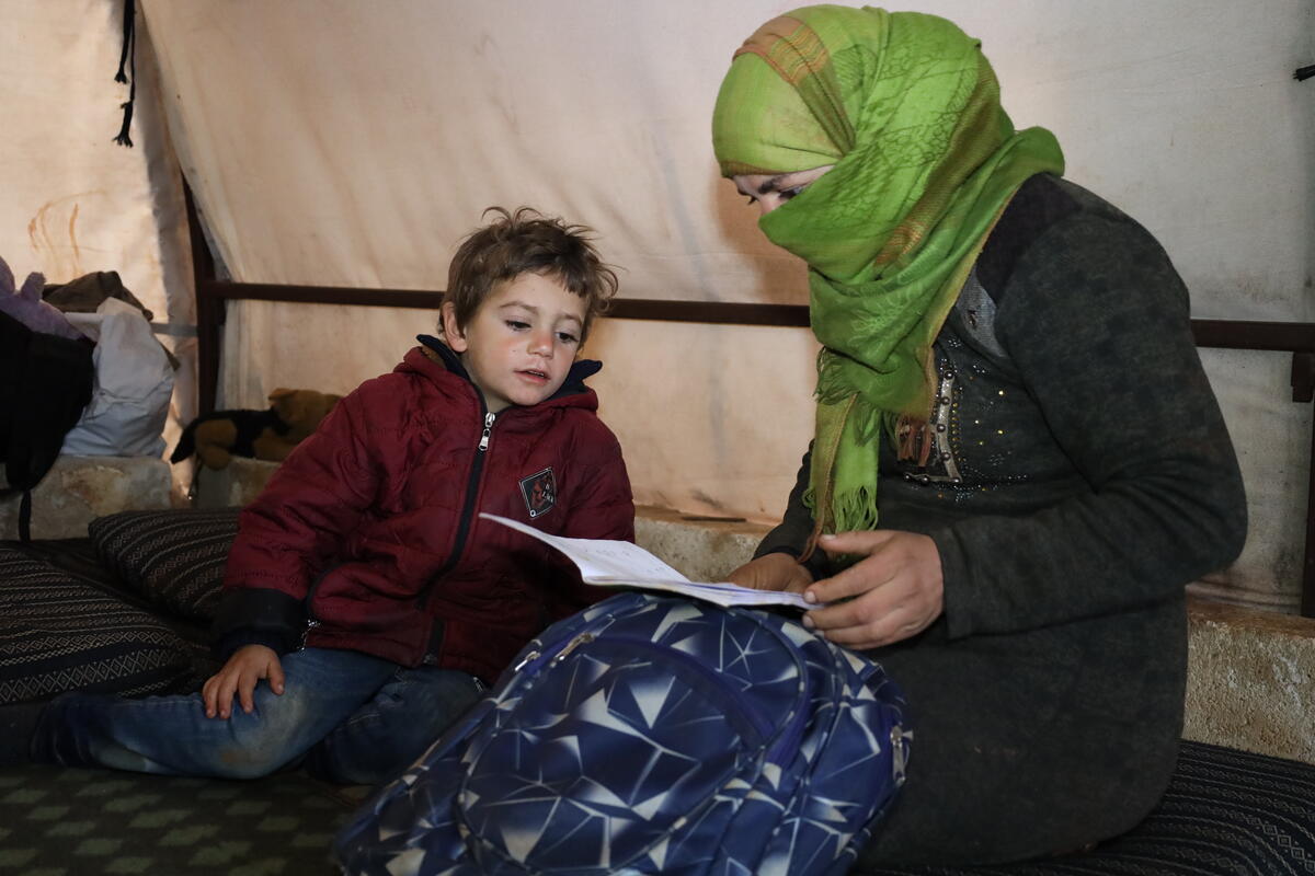 Feryal and her son Weam reading a book together in a tent in Syria